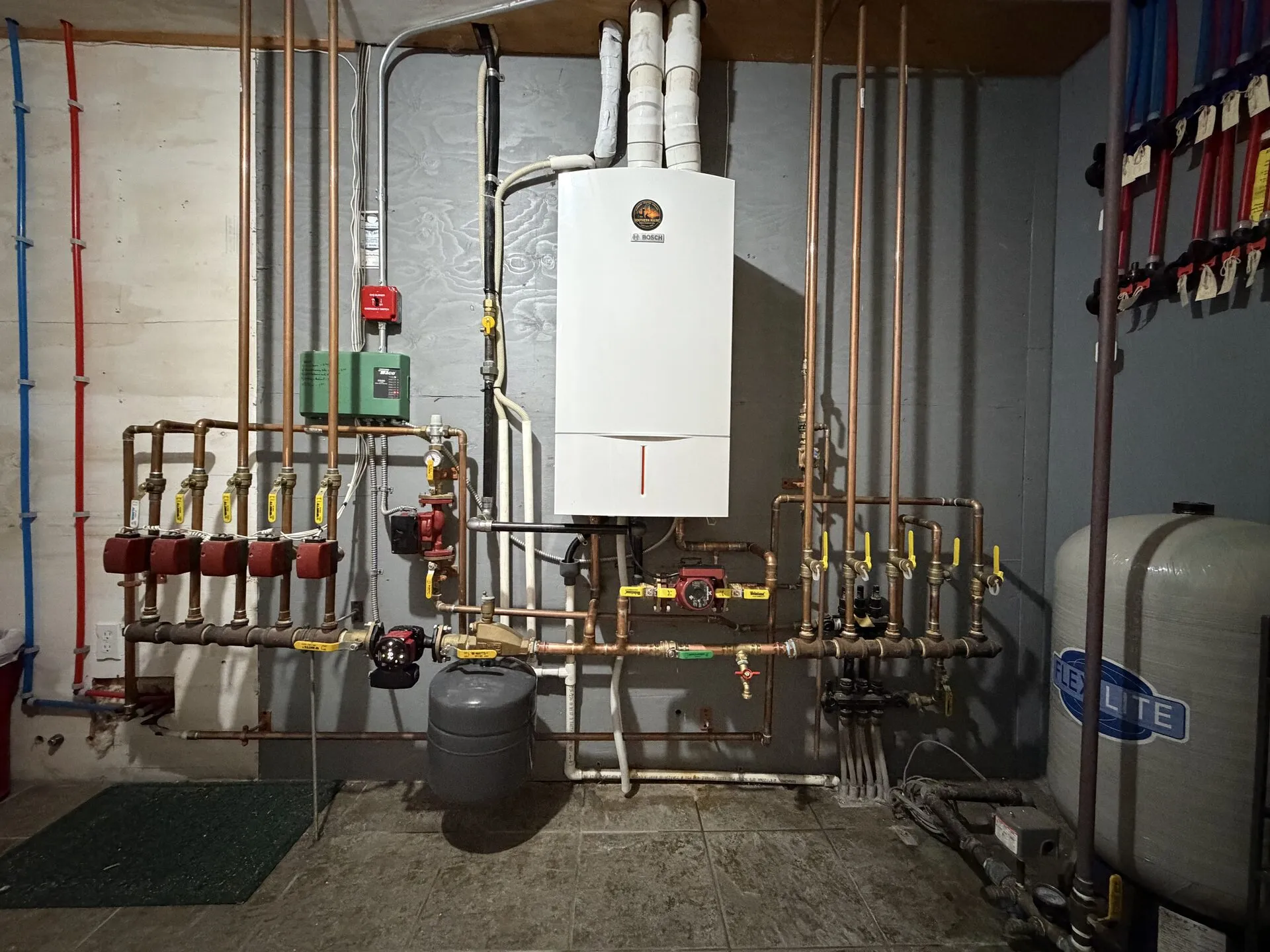 Bosch wall-mounted boiler with copper zone manifold and Taco circulators in a Southern Maine basement