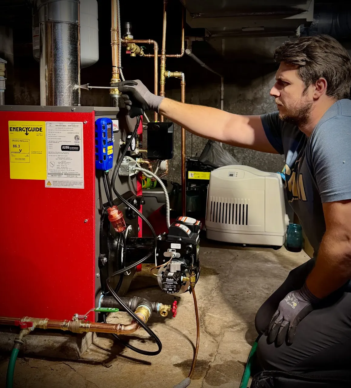 Southern Maine Mechanical owner servicing a high-efficiency red boiler in a Southern Maine basement
